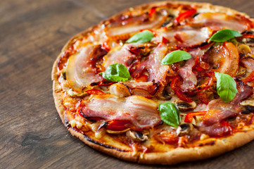 Pizza with Mozzarella cheese, mushrooms, bacon, Tomatoes, pepper, Spices and Fresh Basil. Italian pizza on wooden background.