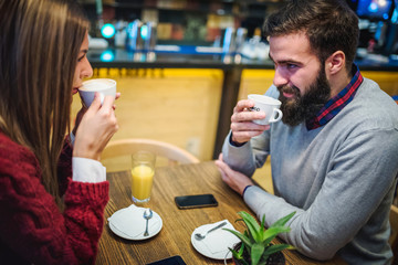 Beautiful couple drinking coffee talking and having fun in cafeteria