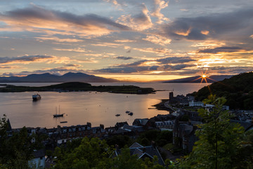 Oban harbor starburst sunset in pink, blue, and yellow in Scotland