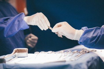 surgery, medicine and people concept - close up of surgeons hands with scalpel at operation in operating room at hospital