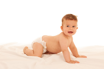 Hapy baby boy in playing on bed isolated over white