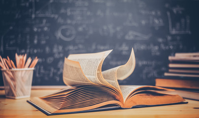 School books on desk formulas and Physics inscription on the blackboard , education concept
