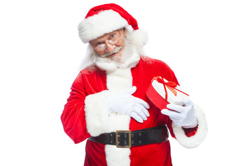 Christmas. Smiling Santa Claus in white gloves holds a red and white heart-shaped gift box with a red ribbon. Isolated on white background.