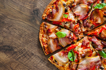 sliced Pizza with Mozzarella cheese, mushrooms, bacon, Tomatoes, pepper, Spices and Fresh Basil. Italian pizza on wooden background.