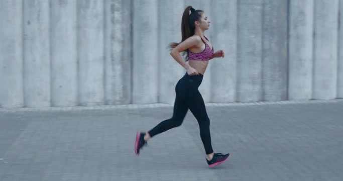 TRACKING Full length shot of fit young woman jogging in the street. Fitness model exercising in morning outdoors. Healthy lifestyle concept. 4K UHD