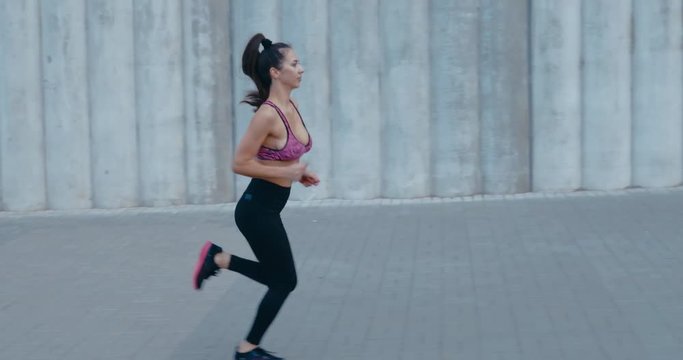 TRACKING Full length shot of fit young woman jogging in the street. Fitness model exercising in morning outdoors. Healthy lifestyle concept. 4K UHD