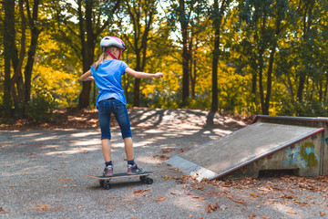 Ein Mädchen skatet mit dem Longboard auf einem Skatepark auf eine Rampe zu