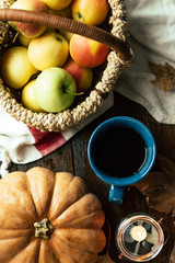 Mug of tea, apples in a basket, pumpkin and fallen leaves, home comfort