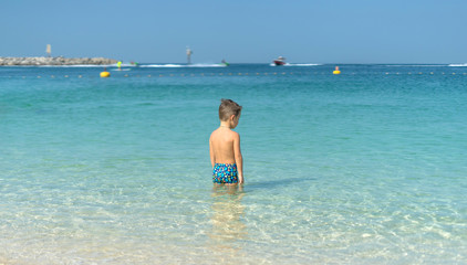 Portrait little boy playing in the sea, ocean. Happy family having fun on tropical white beach. Positive human emotions, feelings. Funny cute child making vacations and enjoying summer.