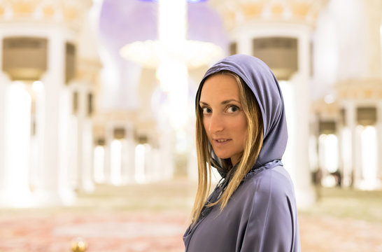Young woman dreaming at the grand mosque of Sheikh Zayed Mosque in Abu Dhabi wearing abaya, paranja in night time. Travelling. Travelling. Concept for advertising poster Dubai, Abu Dhabi.