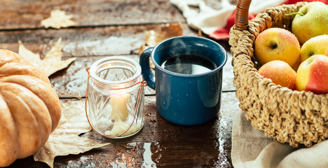 Autumn, a mug of tea and raindrops, fallen leaves, coziness, apples in a basket and pumpkin, long banner
