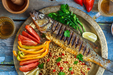 Close view of grilled sea bass with vegetables and ptitim, middle eastern cuisine