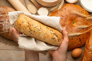 the preparation of bread, fresh bread in hands closeup on old wooden background, concept for baking