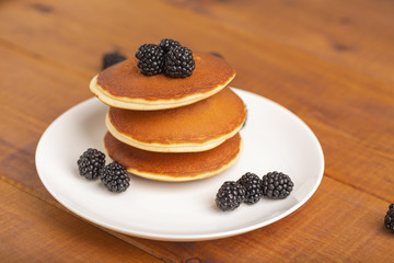 Delicious pancakes with BlackBerry and mint, on a white plate and a wooden table