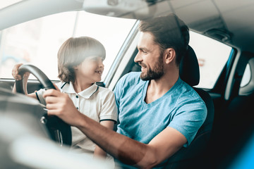 Man With Son Are Sitting At The Wheel Of New Car.