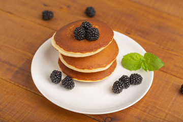 Delicious pancakes with BlackBerry and mint, on a white plate and a wooden table