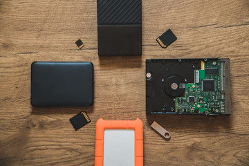 Different types of hard drives disks with different sizes and capacities on a wooden table.