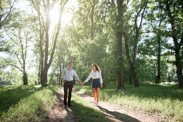 young couple walking in the forest, summer nature, bright sunlight, shadows and green leaves, romantic feelings