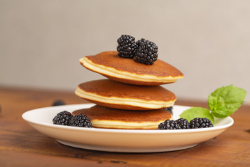 Delicious pancakes with BlackBerry and mint, on a white plate and a wooden table
