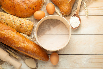 Bread of different varieties on a wood background with copy space background. The concept of bakery, cooking and grocery store.