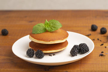 Delicious pancakes with BlackBerry and mint, on a white plate and a wooden table