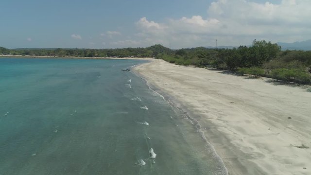 Beautiful tropical beach Cabugao with white sand and palm trees in the Philippines, Luzon. Aerial view of coast with beach and turquoise water.