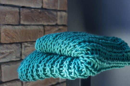 Knitting with knitting needles. A wool snod or scarf. A warm knitted thing in the wardrobe. Volumetric pattern of an elastic band. Winter accessory. Needlework in the form of knitting. 