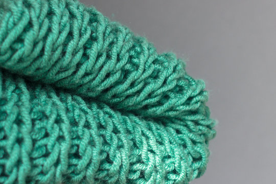 Knitting with knitting needles. A wool snod or scarf. A warm knitted thing in the wardrobe. Volumetric pattern of an elastic band. Winter accessory. Needlework in the form of knitting. 