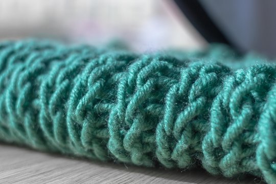 Knitting with knitting needles. A wool snod or scarf. A warm knitted thing in the wardrobe. Volumetric pattern of an elastic band. Winter accessory. Needlework in the form of knitting. 