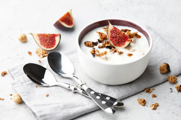 Healthy breakfast concept. Homemade yoghurt with organic granola, nuts and fig fruits in small bowl.