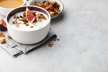 Healthy breakfast concept. Homemade yoghurt with organic granola, nuts and fig fruits in small bowl.