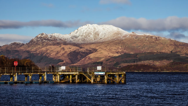 The pier at the village of Luss on the banks of Loch Lomond. The snow covered summit of Ben Lomond dominates the scene.