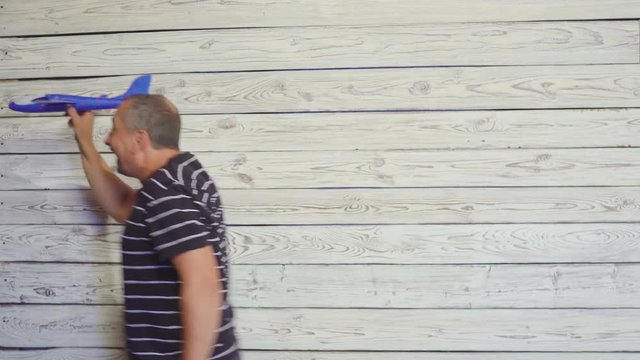 Senior man playing with toy airplane. Funny scene.