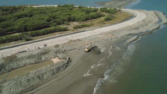 Construction of coastal protective structures, construction of structures to protect against sea waves on Lingayen Beach. Aerial view construction equipment at sea, beach facilities, construction of
