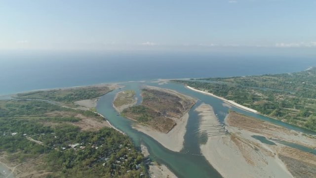 Aerial view of rver flowing into the sea in Philippines,Luzon. ropical landscape with sandy coast and river among farmer fields flowing into the blue ocean