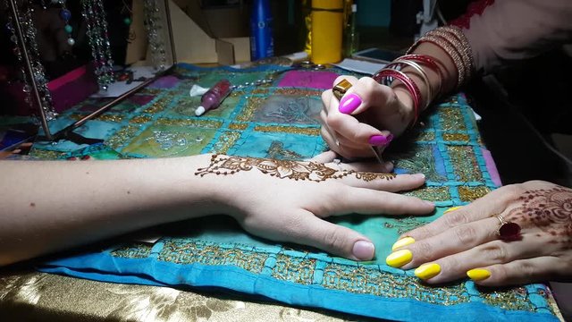 The Master Draws Mehendi On The Girl's Hand. Beautiful Patterns From Henna