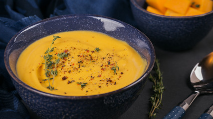 Pumpkin soup in blue bowl topped with fresh herb