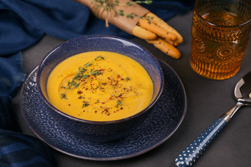 Pumpkin soup in blue bowl topped with fresh herb