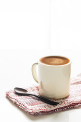 White cup of coffee on white table with bright