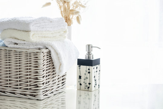 White towels in rattan basket on white table with bright room background