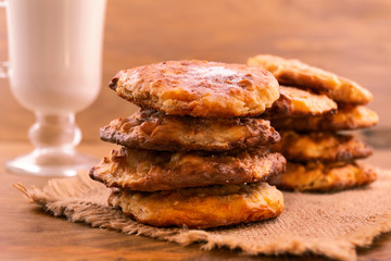 Round home-made cookies, stacked in two piles on a linen napkin, a glass of milk.