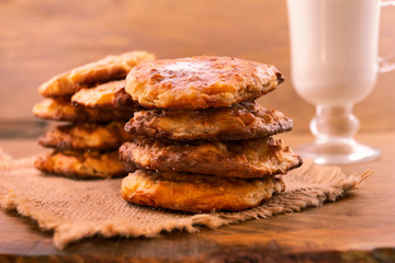 Homemade cakes with cottage cheese on a linen napkin, a glass of milk, wooden background.