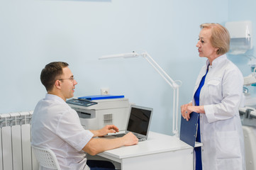 Senior doctor suggest man doctor with laptop in office