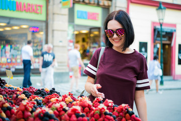 Cheerful happy young woman buying berries on a street market.