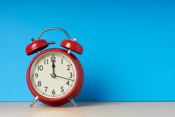 Red alarm clock on blue background with copy space.