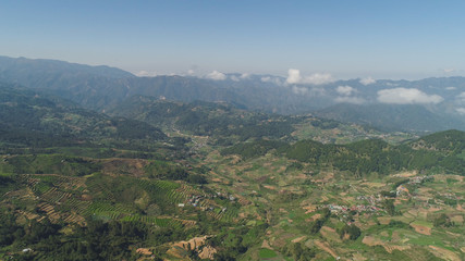 Fototapeta na wymiar Aerial view of rice terraces and agricultural farm land on the slopes of mountains valley. Cultivation of agricultural products in mountain province. Mountains covered forest, trees. Cordillera region