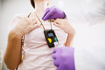 Young cheerful doctor putting Holter monitor device on girls chests.