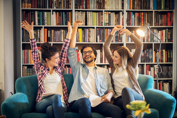 Three happy smiling students celebrating last day of school in library.