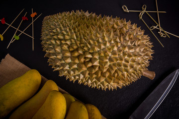 Durian on mango sackcloth with knife, Black stone background