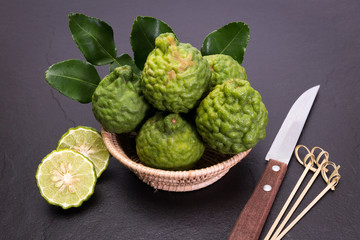 Bergamot, kaffir lime and kaffir lime leaf with basket and knife  on dark background